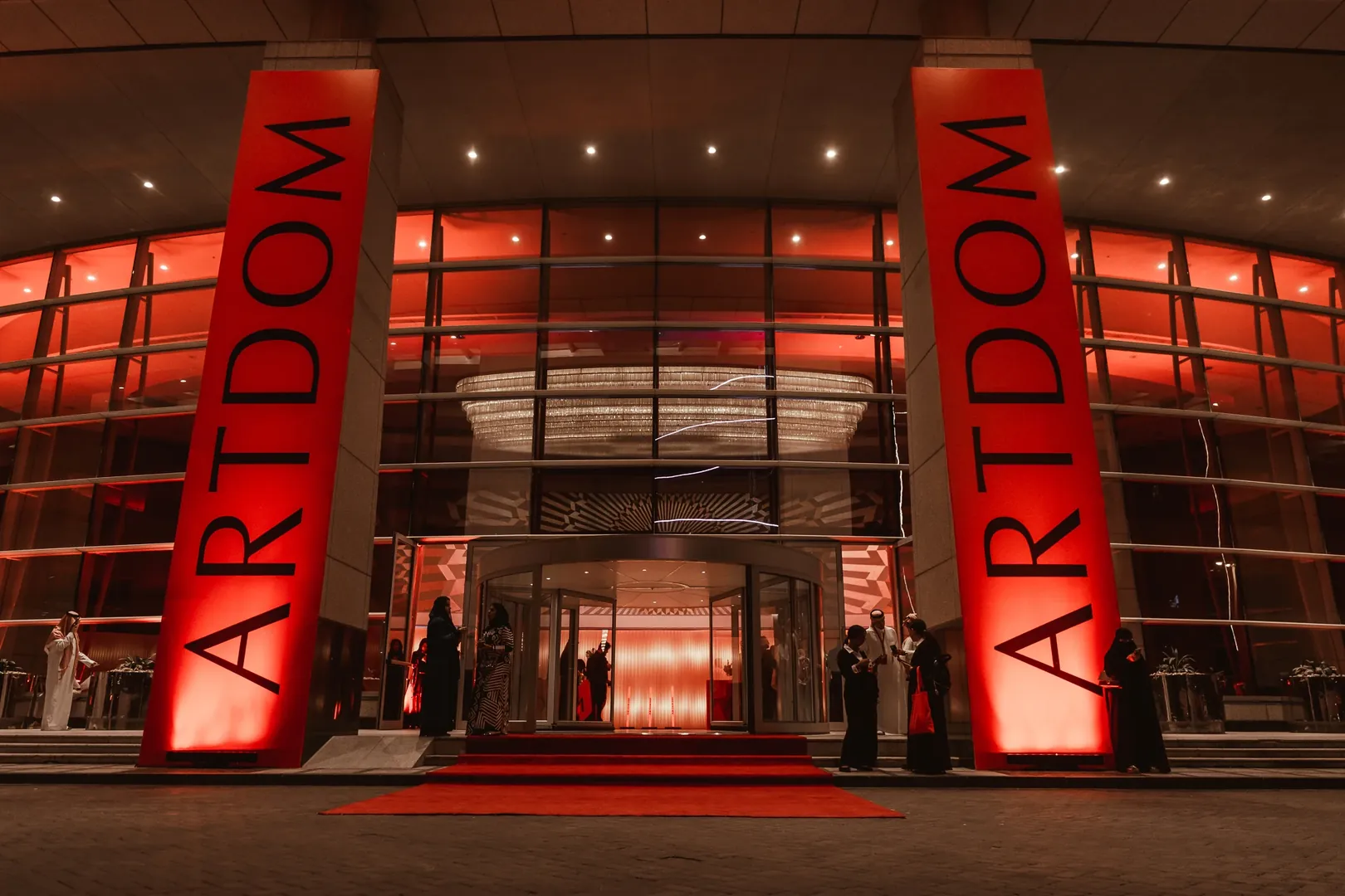 The congress venue at dusk, its columns lit red with the ARTDOM name