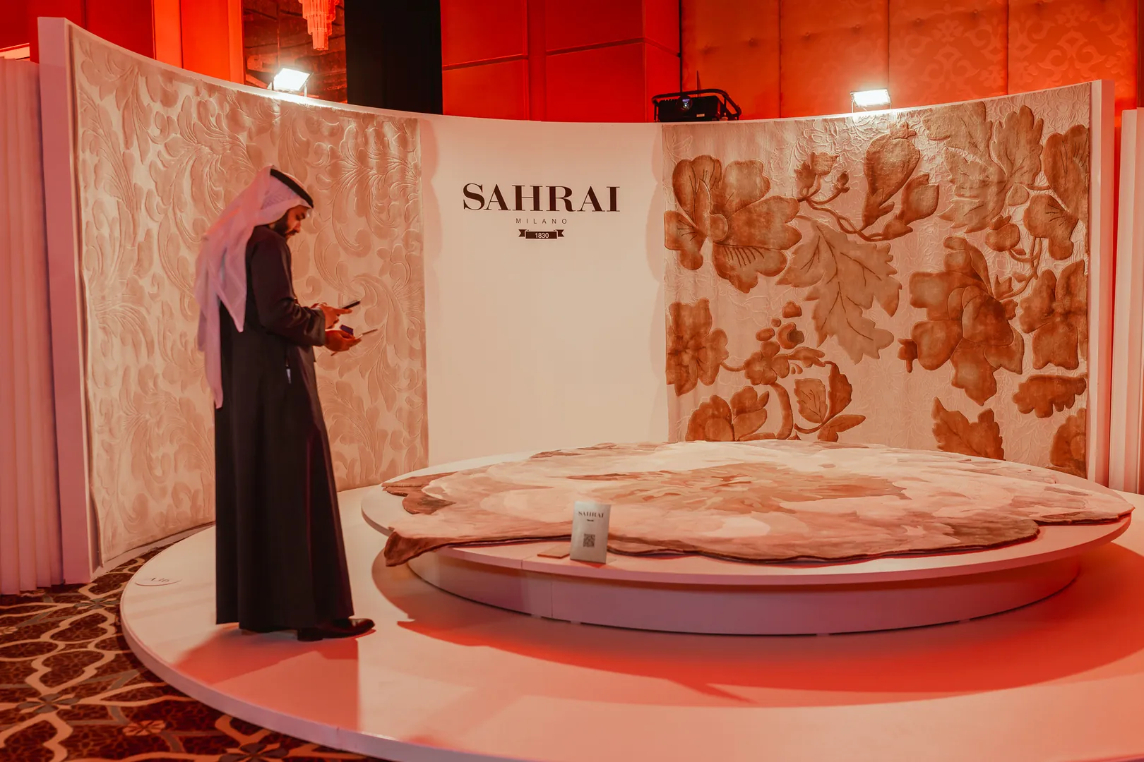 A visitor at the Sahrai stand, a carpet laid out under floral panels