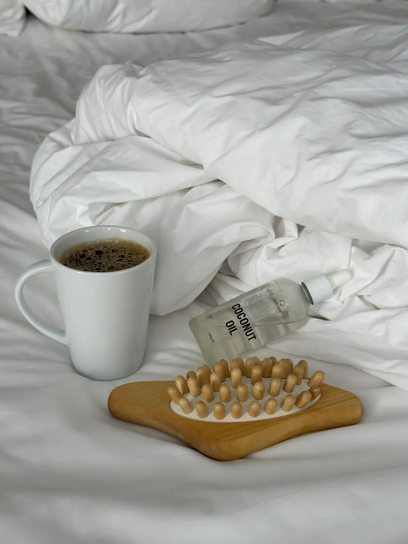 A morning coffee on white sheets beside the massage brush