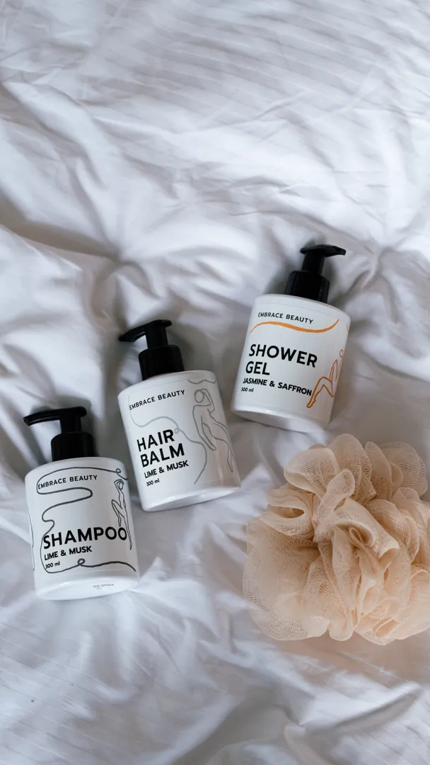 Shampoo, hair balm and shower gel on white sheets