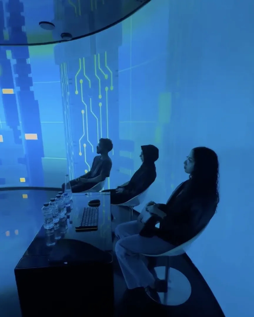 Visitors seated inside the immersive blue projection room