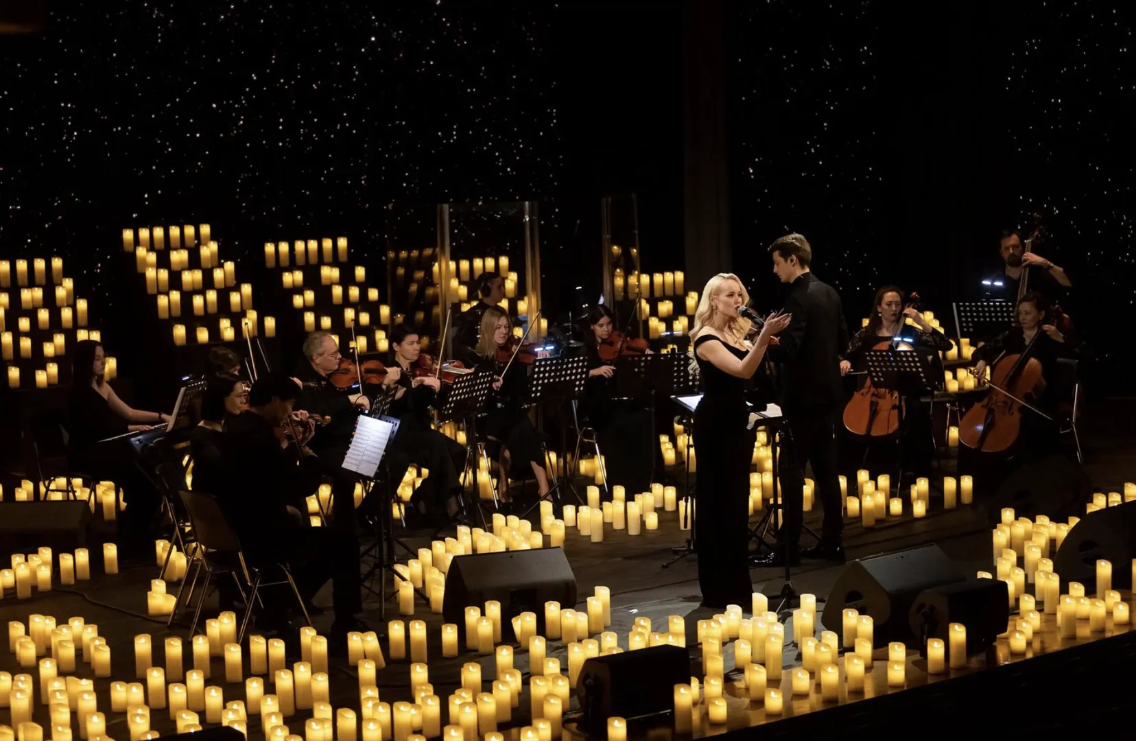 The ensemble on a stage covered in candles