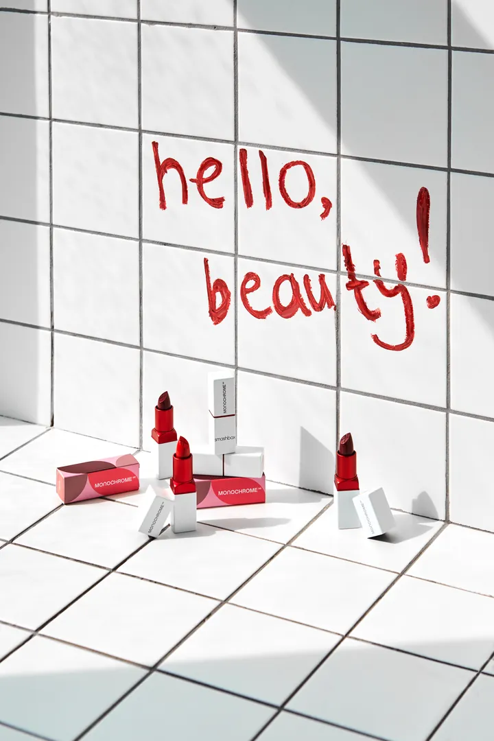 "hello, beauty!" written in lipstick on white tiles above the products