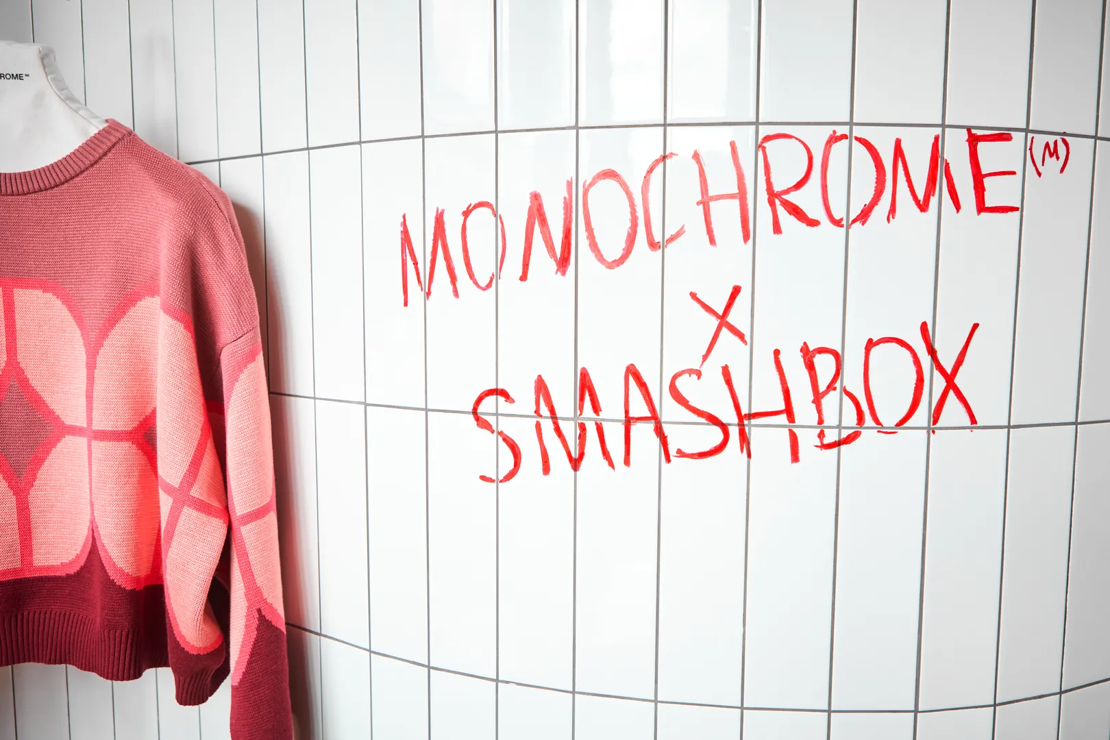 MONOCHROME × SMASHBOX written in lipstick on a tiled wall