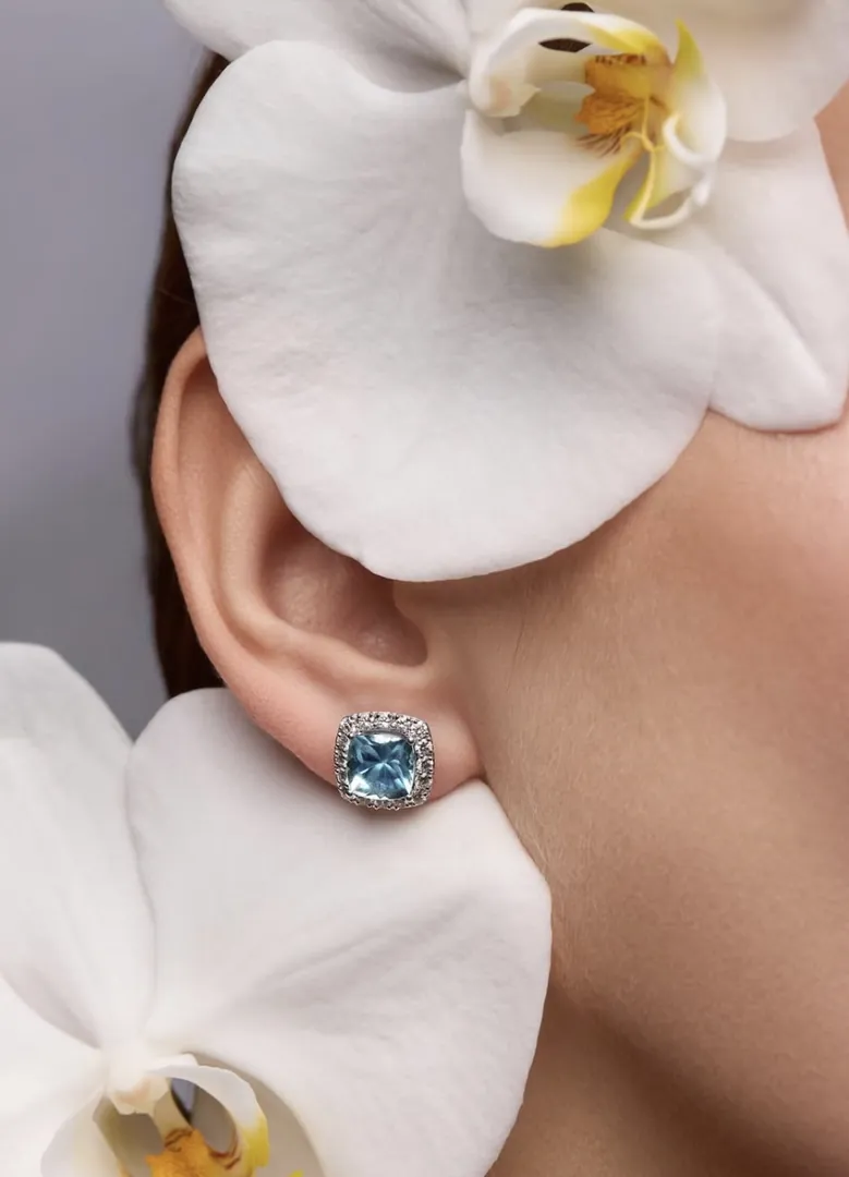 A blue topaz earring framed by white orchids