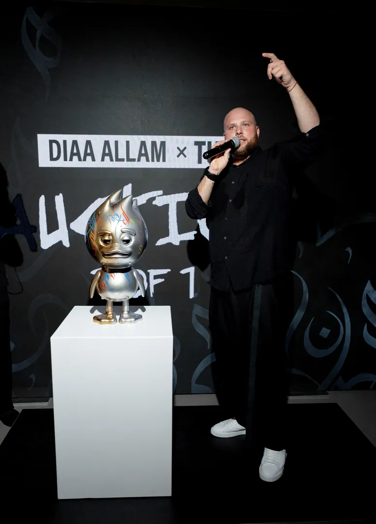 A performer at the microphone beside a figure on a plinth